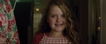 Movie still from “Dumplin'” (2018), directed by Anne Fletcher – A young girl with long red curly hair smiles for the camera; Close Up shot, Over the shoulder angle