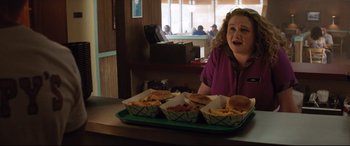 Movie still from “Dumplin'” (2018), directed by Anne Fletcher – A woman sitting in front of a tray of food; Medium shot, Over the shoulder angle
