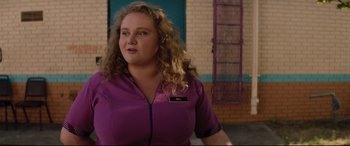Movie still from “Dumplin'” (2018), directed by Anne Fletcher – A woman with curly hair wearing a purple shirt; Close Up shot, Over the shoulder angle