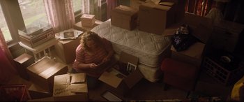 Movie still from “Dumplin'” (2018), directed by Anne Fletcher – A woman sitting on the floor looking at a phone; Wide shot, High angle