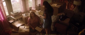 Movie still from “Dumplin'” (2018), directed by Anne Fletcher – Two women in a cluttered living room with boxes; Medium shot, High angle