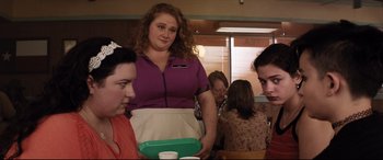 Movie still from “Dumplin'” (2018), directed by Anne Fletcher – A group of people sitting at a table with food; Medium shot, Over the shoulder angle