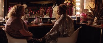 Movie still from “Dumplin'” (2018), directed by Anne Fletcher – A woman sitting at a table in front of a mirror; Medium shot, Over the shoulder angle