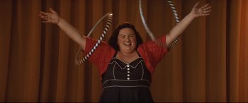 Movie still from “Dumplin'” (2018), directed by Anne Fletcher – A woman in a black and white polka dot dress holding two hula hoops; Medium shot, Low angle