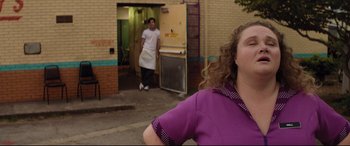 Movie still from “Dumplin'” (2018), directed by Anne Fletcher – A man and a woman are standing in front of a building; Medium shot, Over the shoulder angle