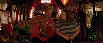 Movie still from “Dumplin'” (2018), directed by Anne Fletcher – Two women sitting next to each other in front of lights; Medium shot, Over the shoulder angle