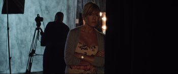 Movie still from “Dumplin'” (2018), directed by Anne Fletcher – A woman with her arms crossed standing in a dark room; Medium shot, Over the shoulder angle