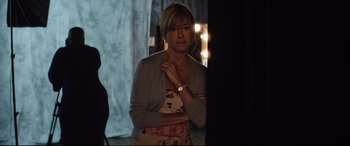 Movie still from “Dumplin'” (2018), directed by Anne Fletcher – A woman standing in front of a curtain; Medium shot, Over the shoulder angle