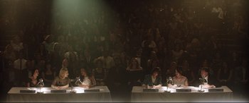 Movie still from “Dumplin'” (2018), directed by Anne Fletcher – A group of people sitting in front of an audience; Wide shot, High angle