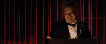Movie still from “Dumplin'” (2018), directed by Anne Fletcher – A man in a tuxedo smiling for the camera; Close Up shot, Low angle