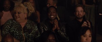 Movie still from “Dumplin'” (2018), directed by Anne Fletcher – A woman claps her hands while sitting in a crowd; Close Up shot, High angle
