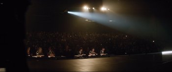 Movie still from “Dumplin'” (2018), directed by Anne Fletcher – A group of people sitting in front of microphones in front of an audience; Extreme Wide shot, High angle