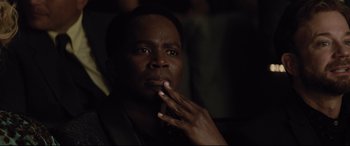 Movie still from “Dumplin'” (2018), directed by Anne Fletcher – A man with his hand to his face looking at the camera; Close Up shot, High angle