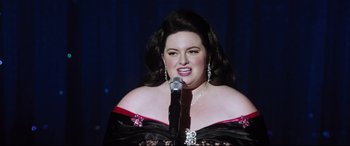 Movie still from “Dumplin'” (2018), directed by Anne Fletcher – A woman in a black and red dress singing into a microphone; Close Up shot, Over the shoulder angle
