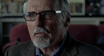 Movie still from “Elegy” (2008), directed by Isabel Coixet – An older man with a beard wearing glasses and a jacket; Close Up shot, Over the shoulder angle