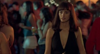 Movie still from “Elegy” (2008), directed by Isabel Coixet – A woman in a black dress standing in front of a group of people; Close Up shot, Over the shoulder angle