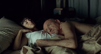 Movie still from “Elegy” (2008), directed by Isabel Coixet – A man and a woman laying in bed together; Medium shot, Overhead angle