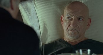 Movie still from “Elegy” (2008), directed by Isabel Coixet – An older man sitting in a chair looking at the camera; Close Up shot, Over the shoulder angle