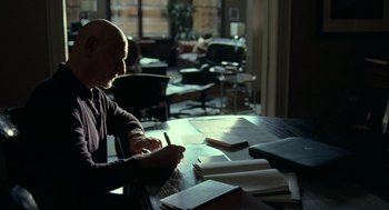 Movie still from “Elegy” (2008), directed by Isabel Coixet – A man sitting at a table writing on a piece of paper; Medium shot, High angle