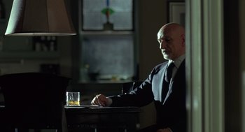 Movie still from “Elegy” (2008), directed by Isabel Coixet – An older man sitting at a table with a glass of whiskey; Medium shot, Over the shoulder angle