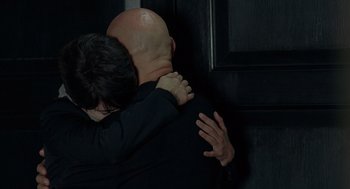 Movie still from “Elegy” (2008), directed by Isabel Coixet – A man and a woman hugging in front of a black wall; Medium shot, Over the shoulder angle