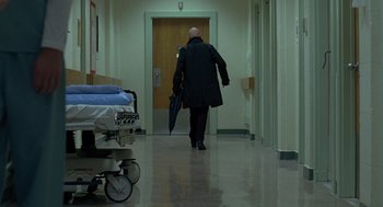 Movie still from “Elegy” (2008), directed by Isabel Coixet – A man walking down a hallway holding an umbrella; Wide shot, Low angle