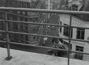 Movie still from “Elevator to the Gallows” (1958), directed by Louis Malle – A person on a balcony with a rope attached to a railing; Medium shot, High angle