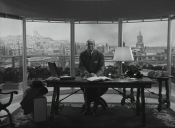 Movie still from “Elevator to the Gallows” (1958), directed by Louis Malle – A man sitting at a desk in front of a large window; Wide shot, Low angle