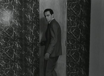 Movie still from “Elevator to the Gallows” (1958), directed by Louis Malle – A black and white photo of a man in a suit; Medium shot, Low angle