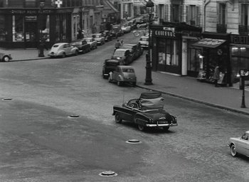 Movie still from “Elevator to the Gallows” (1958), directed by Louis Malle – An old black and white photo of a car on the street; Extreme Wide shot, High angle
