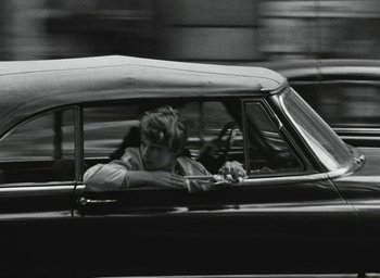 Movie still from “Elevator to the Gallows” (1958), directed by Louis Malle – A woman sitting in the driver's seat of a car; Wide shot, Over the shoulder angle