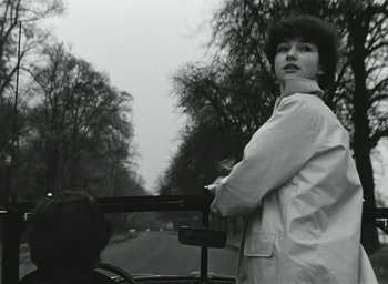 Movie still from “Elevator to the Gallows” (1958), directed by Louis Malle – A black and white photo of a woman riding a bike; Medium shot, Low angle