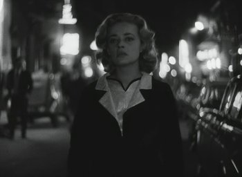 Movie still from “Elevator to the Gallows” (1958), directed by Louis Malle – A black and white photo of a woman in a suit; Medium shot, Low angle