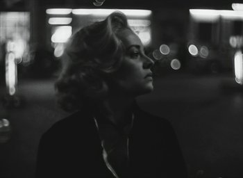 Movie still from “Elevator to the Gallows” (1958), directed by Louis Malle – A black and white photo of a woman in a suit and tie; Close Up shot, Low angle