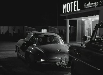 Movie still from “Elevator to the Gallows” (1958), directed by Louis Malle – A car parked in front of a motel at night; Wide shot, Over the shoulder angle