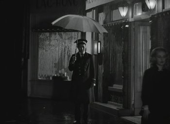 Movie still from “Elevator to the Gallows” (1958), directed by Louis Malle – A man holding an umbrella while standing in the rain; Wide shot, Low angle