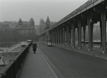 Movie still from “Elevator to the Gallows” (1958), directed by Louis Malle – Two people walking on a bridge near a train; Extreme Wide shot, High angle