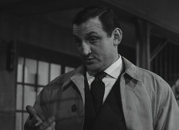 Movie still from “Elevator to the Gallows” (1958), directed by Louis Malle – A man wearing a suit and tie in a black and white photo; Close Up shot, Low angle