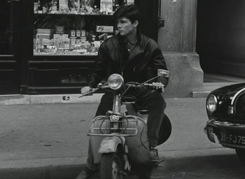 Movie still from “Elevator to the Gallows” (1958), directed by Louis Malle – A man riding a scooter down the street; Wide shot, High angle