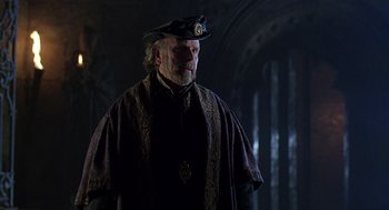 Movie still from “Elizabeth” (1998), directed by Shekhar Kapur – An older man in a hat and a cape; Medium shot, Over the shoulder angle