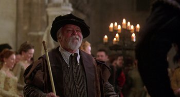 Movie still from “Elizabeth” (1998), directed by Shekhar Kapur – An old man with a beard wearing a hat; Medium shot, Over the shoulder angle