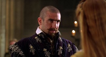 Movie still from “Elizabeth” (1998), directed by Shekhar Kapur – A man with a beard and a purple jacket; Close Up shot, Over the shoulder angle