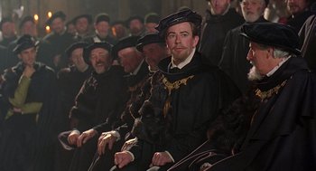 Movie still from “Elizabeth” (1998), directed by Shekhar Kapur – A group of men sitting next to each other; Medium shot, Over the shoulder angle