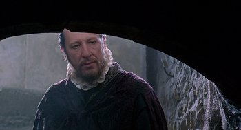 Movie still from “Elizabeth” (1998), directed by Shekhar Kapur – A man with a long beard wearing a purple and black outfit; Close Up shot, Over the shoulder angle
