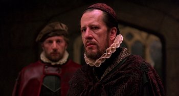 Movie still from “Elizabeth” (1998), directed by Shekhar Kapur – Two men in medieval garb looking at the camera; Close Up shot, Over the shoulder angle