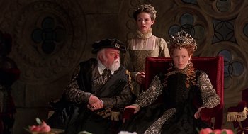 Movie still from “Elizabeth” (1998), directed by Shekhar Kapur – A group of three people sitting next to each other; Medium shot, Over the shoulder angle