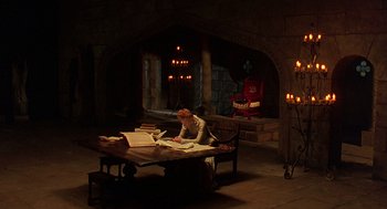 Movie still from “Elizabeth” (1998), directed by Shekhar Kapur – A woman sitting at a table in front of candles; Wide shot, High angle