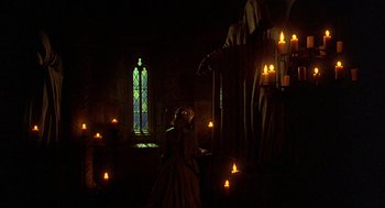 Movie still from “Elizabeth” (1998), directed by Shekhar Kapur – A woman standing in front of a stained glass window; Wide shot, Low angle
