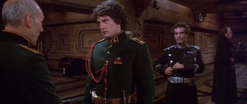 Movie still from “Dune” (1984), directed by David Lynch – A man in a military uniform standing next to another man; Medium shot, Low angle