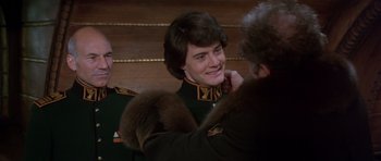 Movie still from “Dune” (1984), directed by David Lynch – A man in a military uniform is smiling while another man adjusts his collar; Close Up shot, Over the shoulder angle